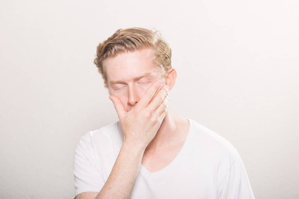 Man with hand over his mouth in shock and eyes closed