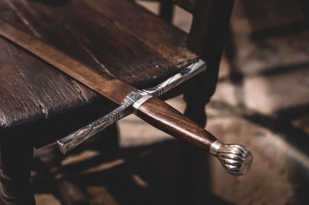 Old fashioned wooden sword resting on an old wooden chair